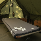 Camping cot with a gray blanket and rope in front of a green tent.