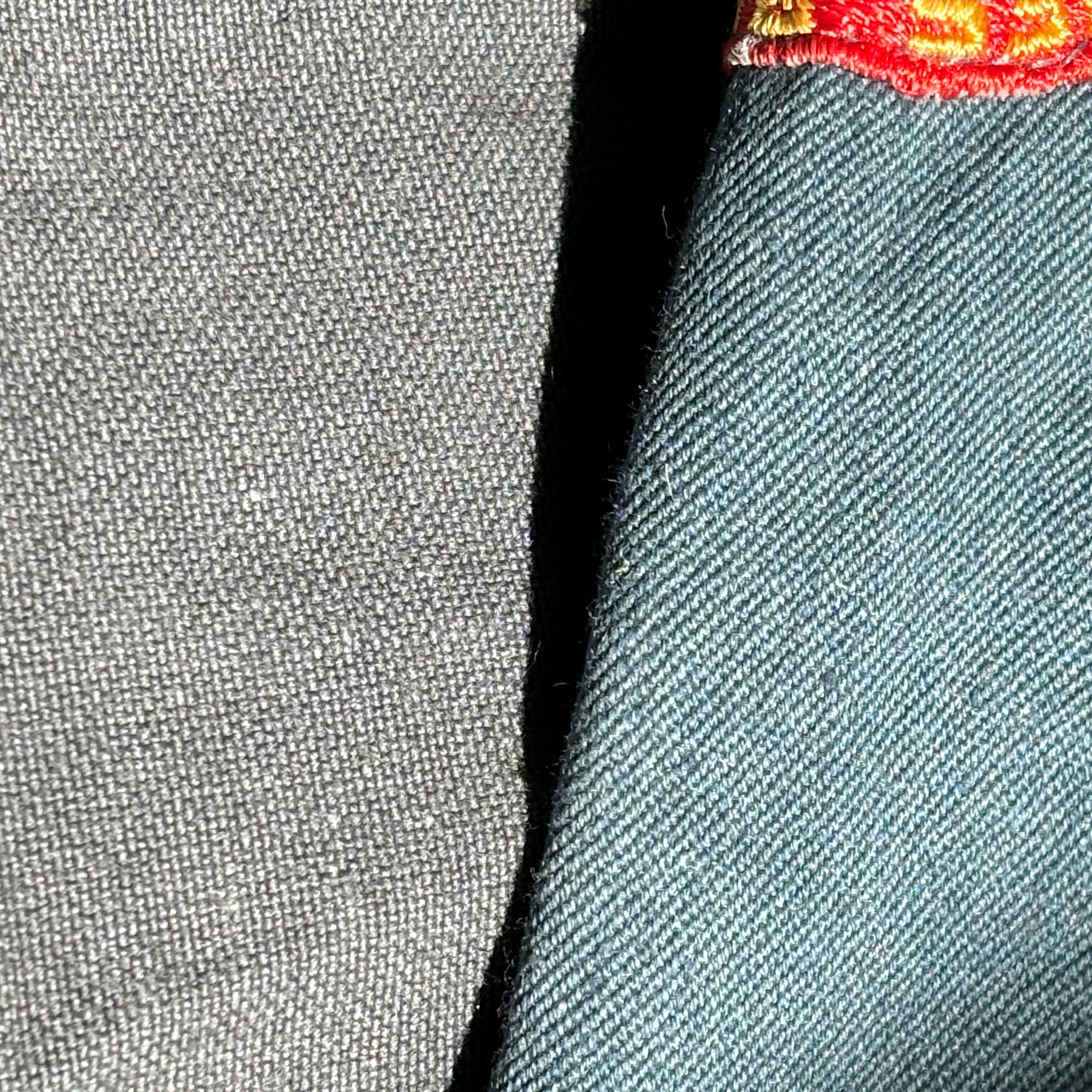 Close-up of gray fabric with a red and yellow logo on the corner.